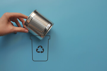 A man throws a metal can into a dumpster .Sorting and recycling of garbage