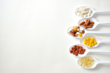 Tablets, capsules, dietary supplements, vitamins on spoons. Medical background