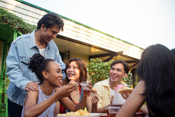 A man arrives in the middle of a picnic with close friends, enjoying pizza outside in the yard. Captures fun, joy, and togetherness.