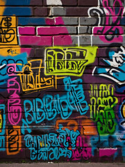 Colorful tags and graffiti covering a city wall in a burst of hues.