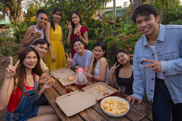 Nine close friends share a selfie together during a nice picnic outdoors by the backyard enjoying pizza and drinks.