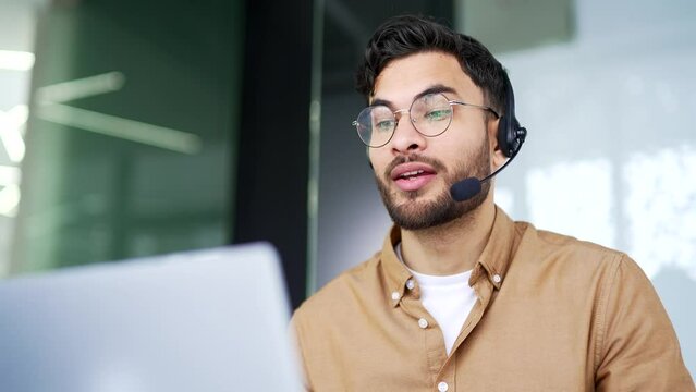 Corporate operator who works in customer support speaks on a video call using a laptop computer. Call center agent in wireless headset helping with complaints in office. Online consultation. Close up 