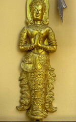 Golden Thai Buddhist Idol statue in Chiang Mai Thailand symbolizing worship at tourist temple.