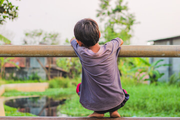 Portrait of child enjoying playing hanging from a bridge pillar