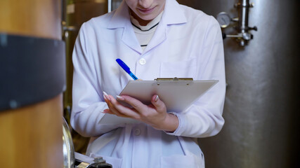 Winemaker woman checking and examining producing wine at winery in factory, inspector checking...