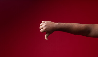 Thumb down Male hand isolated on red background with copy space dislike concept image