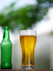 Light cold beer glass on the table in the summer garden