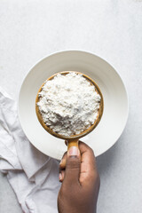 Overhead view of All purpose flour in a brown ceramic measuring cup, one cup of flour