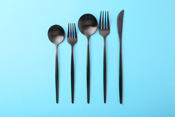 Stylish cutlery set on light blue table, flat lay
