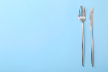 Stylish cutlery on light blue table, top view. Space for text