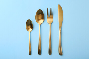 Stylish cutlery set on light blue table, flat lay