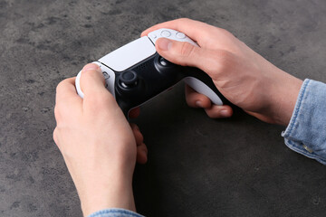 Man using wireless game controller at grey table, closeup