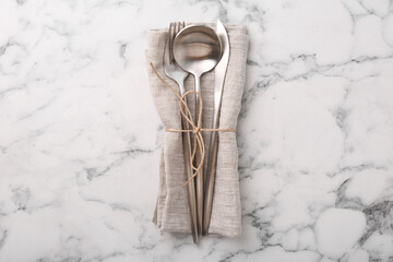 Set of stylish cutlery and napkin on white marble table, top view