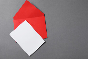 Blank sheet of paper and letter envelope on grey background, top view. Space for text