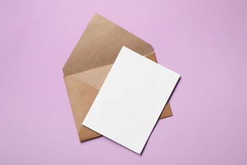 Letter envelope and card on violet background, top view. Space for text