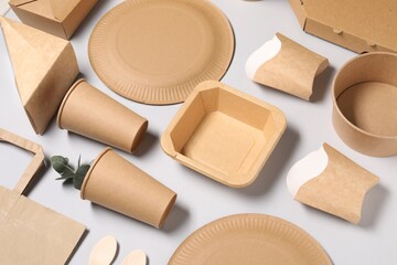 Eco friendly food packaging. Paper containers, tableware and eucalyptus leaves on light grey background