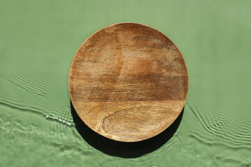 Presentation for product. Wooden podium in water on green background, top view