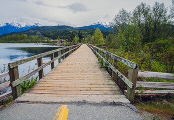 Wooden footbridge over lake with spectacular mountain backdrop on Valley Trail, Whistler, BC.