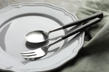 Stylish setting with cutlery, napkin and plate on table, closeup