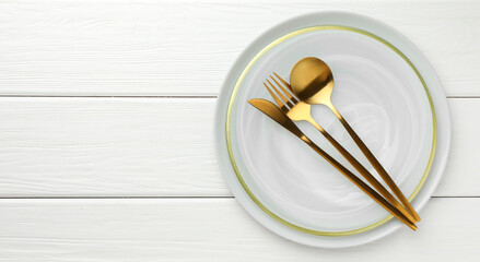Stylish setting with cutlery and plate on white wooden table, top view. Space for text