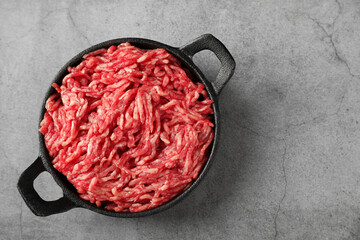 Raw ground meat in bowl on grey table, top view. Space for text