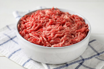 Raw ground meat in bowl on table, closeup