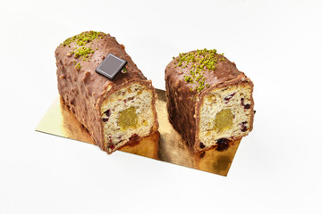 Sliced fruitcake with dried berries, milk chocolate glaze and pistachio