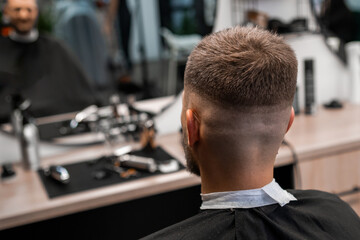 Client sitting after cutting hair in the barbershop.