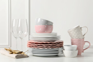 Beautiful ceramic dishware, glasses, cups and cutlery on white marble table