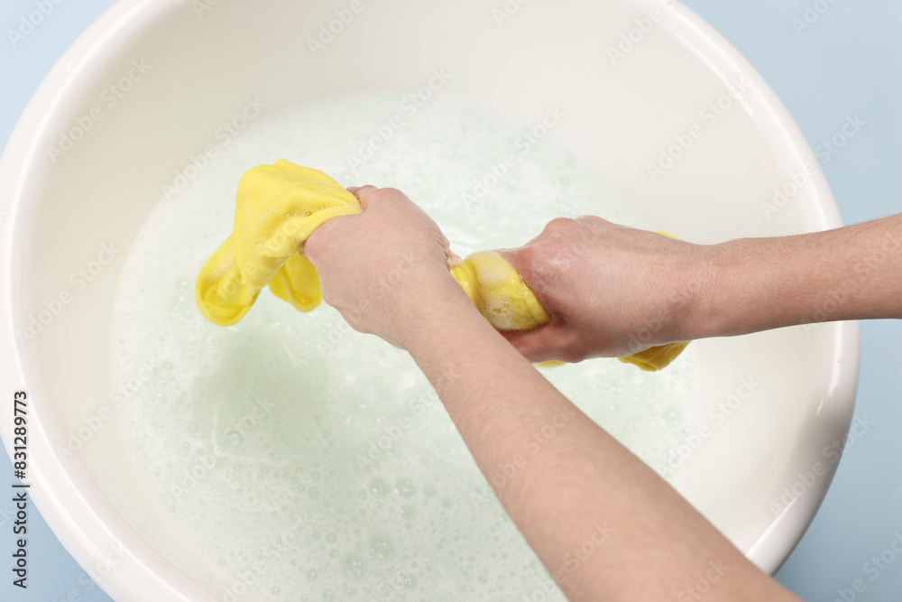 Canvas Prints Woman washing baby clothes in basin on light blue background, closeup