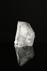Obraz premium Piece of clear ice on black mirror surface