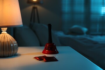 Ring for sex bell and condoms on bedside table in bedroom at night
