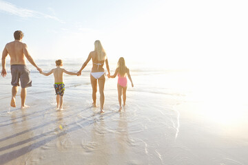 Support, walking and family holding hands at a beach for summer, fun and bonding at sunset...