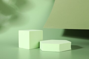 Presentation of product. Podiums, paper and shadows on green background. Space for text