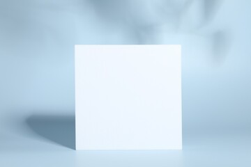 Presentation of product. White podium and shadows on light blue background. Space for text