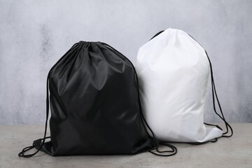 Two drawstring bags on grey textured table