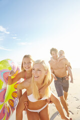 Family, piggyback and fun with children at beach in swimsuit for holiday trip, summer vacation or weekend getaway. Playing, parents and happy kids for travel, adventure or bonding together at sea © Grady Reese/peopleimages.com