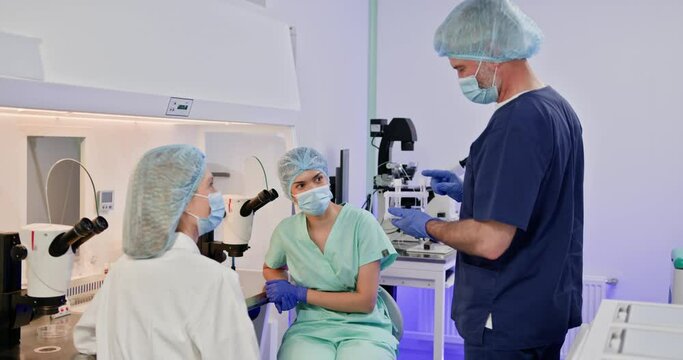 A team of embryologists performing artificial fertilization in a laboratory. The scene depicts scientific collA team of embryologists performing artificial fertilization in a laboratory. The scene