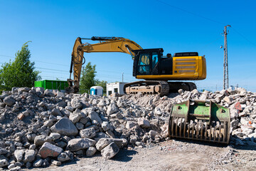 Yellow excavator standing on a pile of concrete boulders