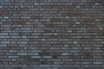 Facade of a brick wall of a gray building with straight rows.