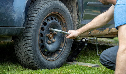 A skilled man with tools in hand, fixing a tire on a massive truck under the bright sun.