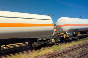 A coupling of two white railway tanks with a longitudinal orange stripe.