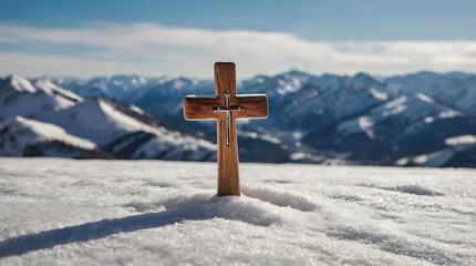 A close-up detailed image of a small wooden Christian cross in middle of snow and snowy mountains in background and copy space
