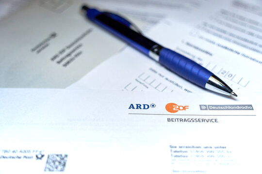 Close-up of ARD and ZDF, GEZ documents with a blue pen, indicating German public broadcasting service paperwork.