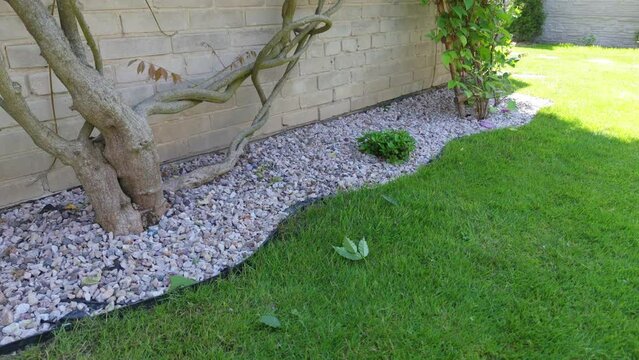 Gravel and lawn in home garden slow motion. Gardening concept background. Lawn edge close up summer
