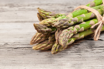 A bunch of fresh asparagus spears tied with twine rests on a rustic wooden table, perfect for a healthy meal.