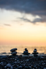 Three large rocks are stacked on top of each other on a beach