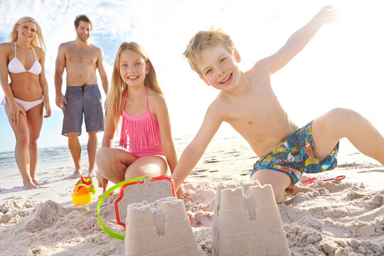 Happy, family and building sandcastles at beach for freedom, fun and relax on summer holiday in Bali. Excited, kids and parents with smile for bonding and playing together on vacation to Indonesia