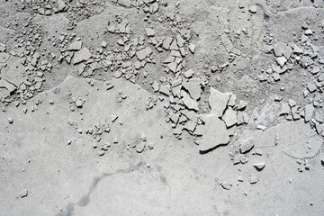 Damaged concrete floor with pieces of cement plaster and cracks