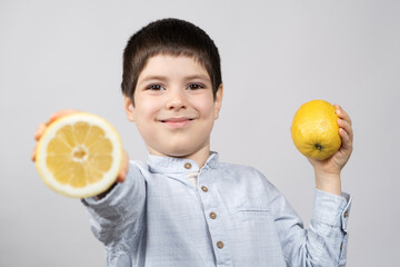 A happy six-year-old boy holds lemons in his hands and smiles